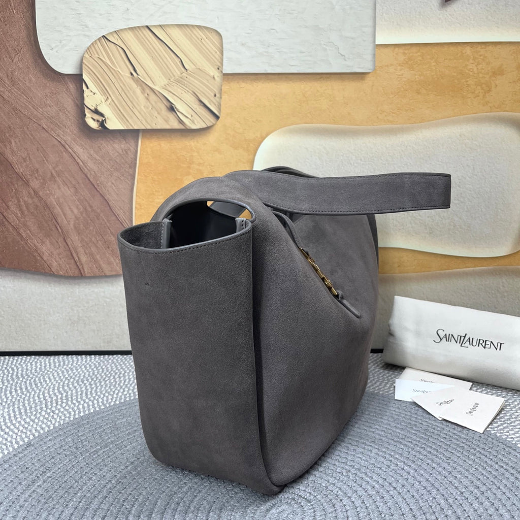 Dark gray suede tote bag shown from side with top handles and gold zipper detail