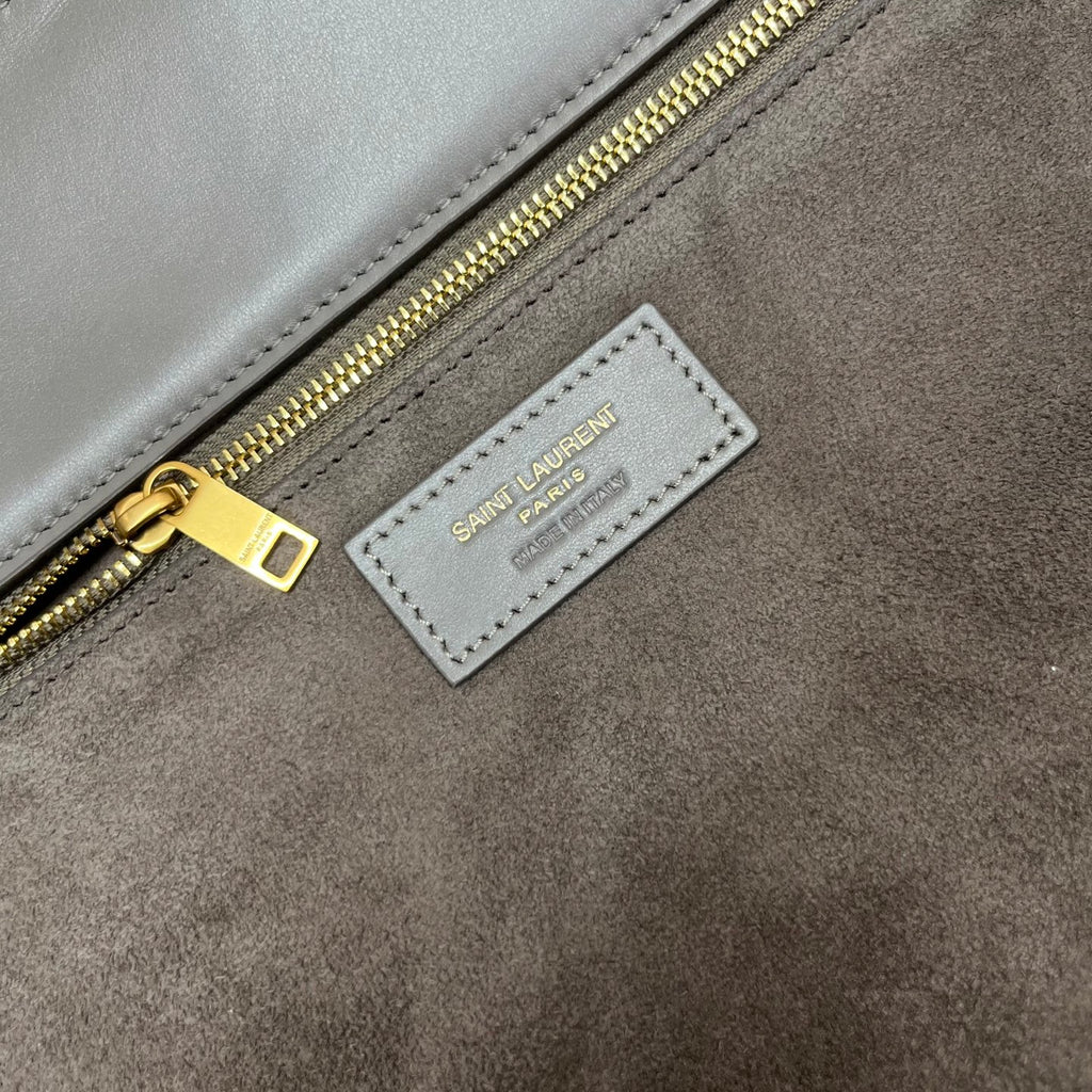 Gray suede tote label reading "SAINT LAURENT" with gold zipper pull