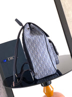 Dior logo-print backpack in blue tones, shown from the side with top handle.