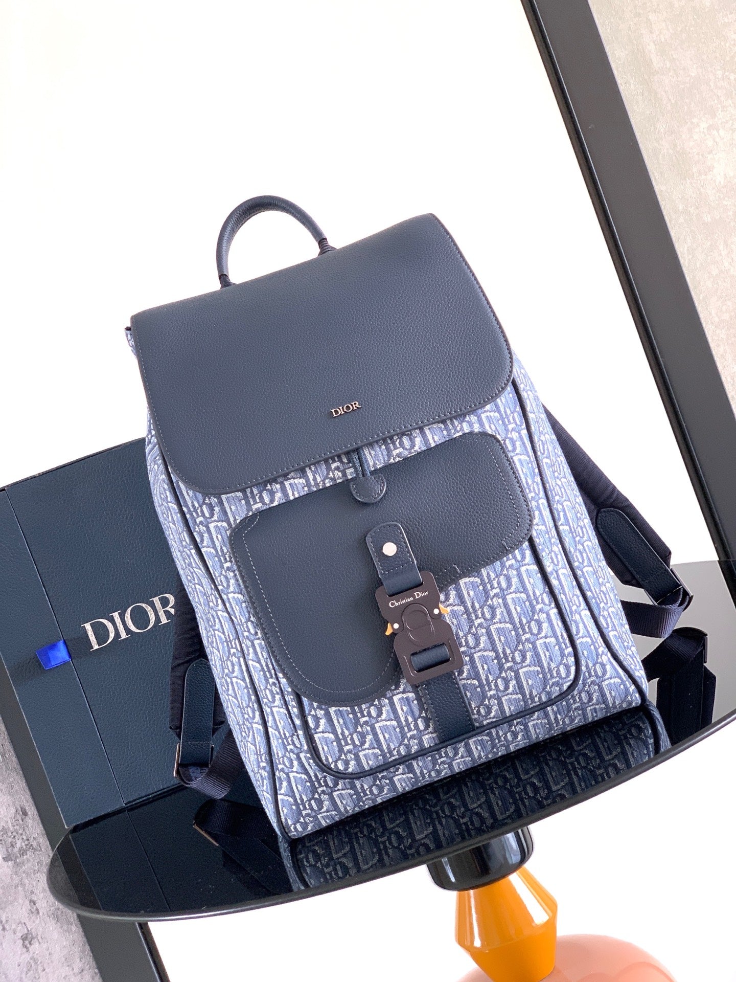 Navy Dior backpack bag with flap, textured leather front pocket, and top handle loop.