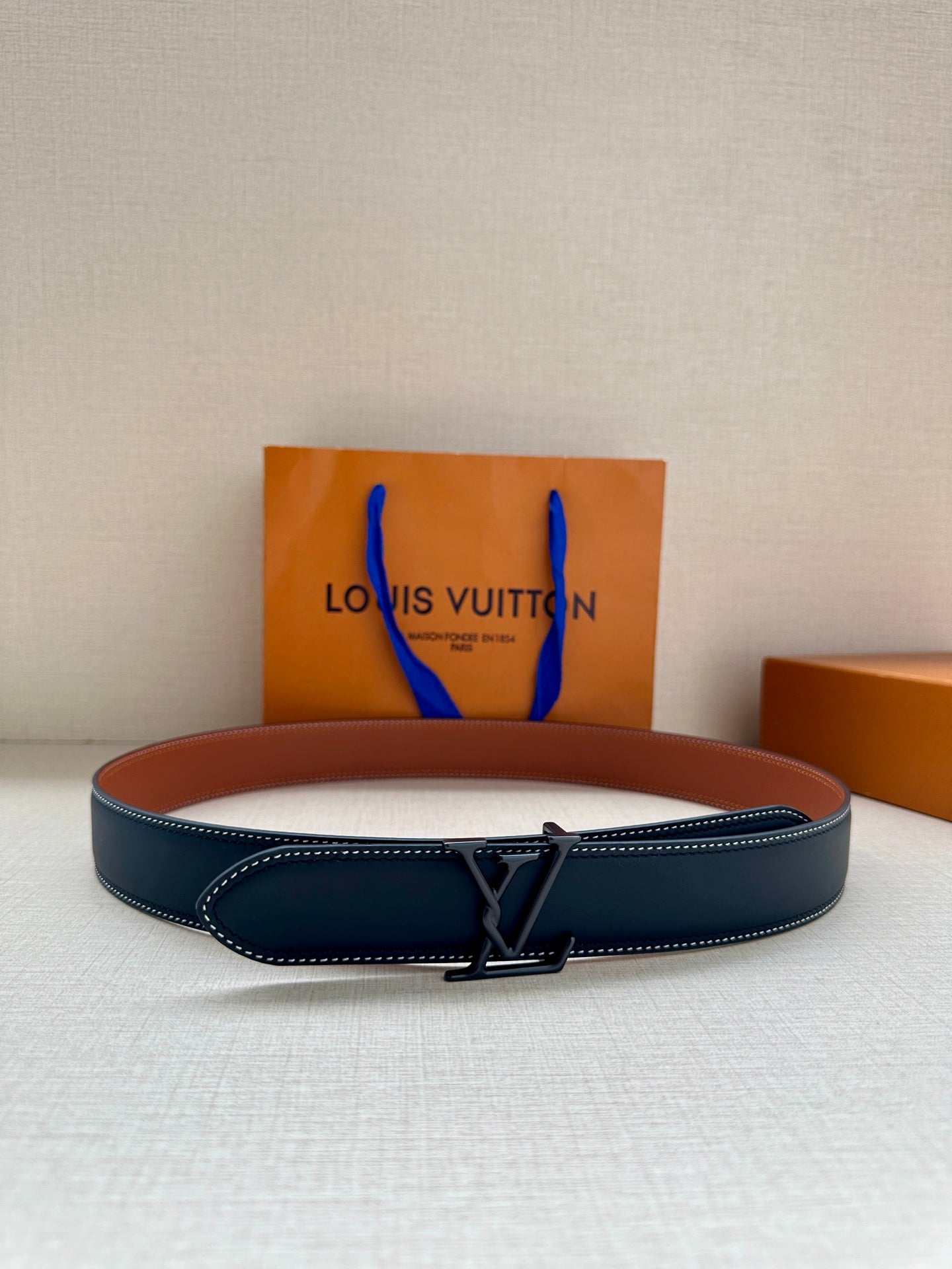 Louis Vuitton leather belt, dark blue with silver buckle and white edge stitching.
