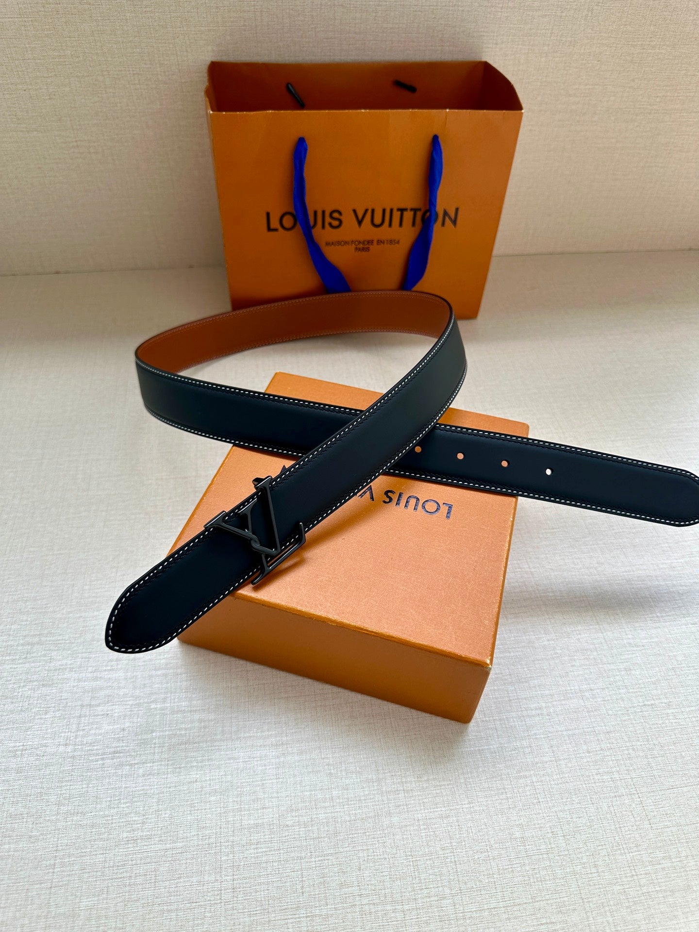 Louis Vuitton leather belt, dark blue with silver buckle and white edge stitching.