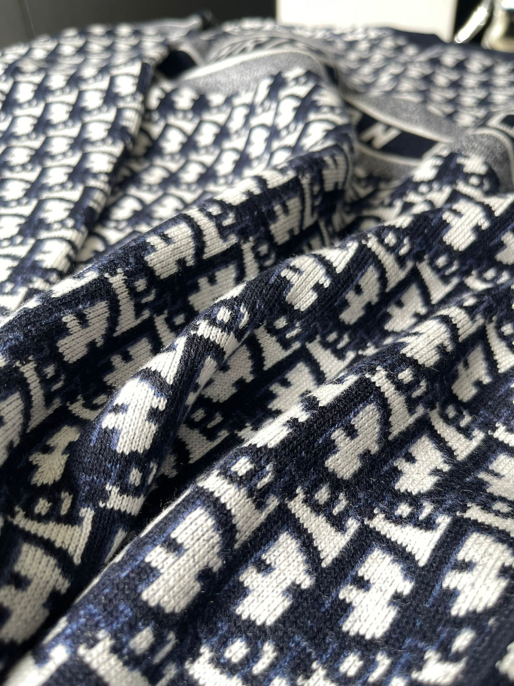 Dior long-sleeve sweater fabric close-up with navy and white repeating logo knit