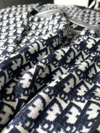 Dior long-sleeve sweater fabric close-up with navy and white repeating logo knit