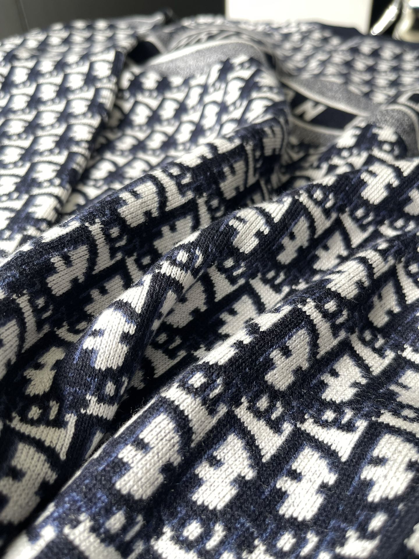 Dior long-sleeve sweater fabric close-up with navy and white repeating logo knit