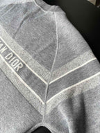 Gray long-sleeve sweater close-up with striped trim and V seam detail