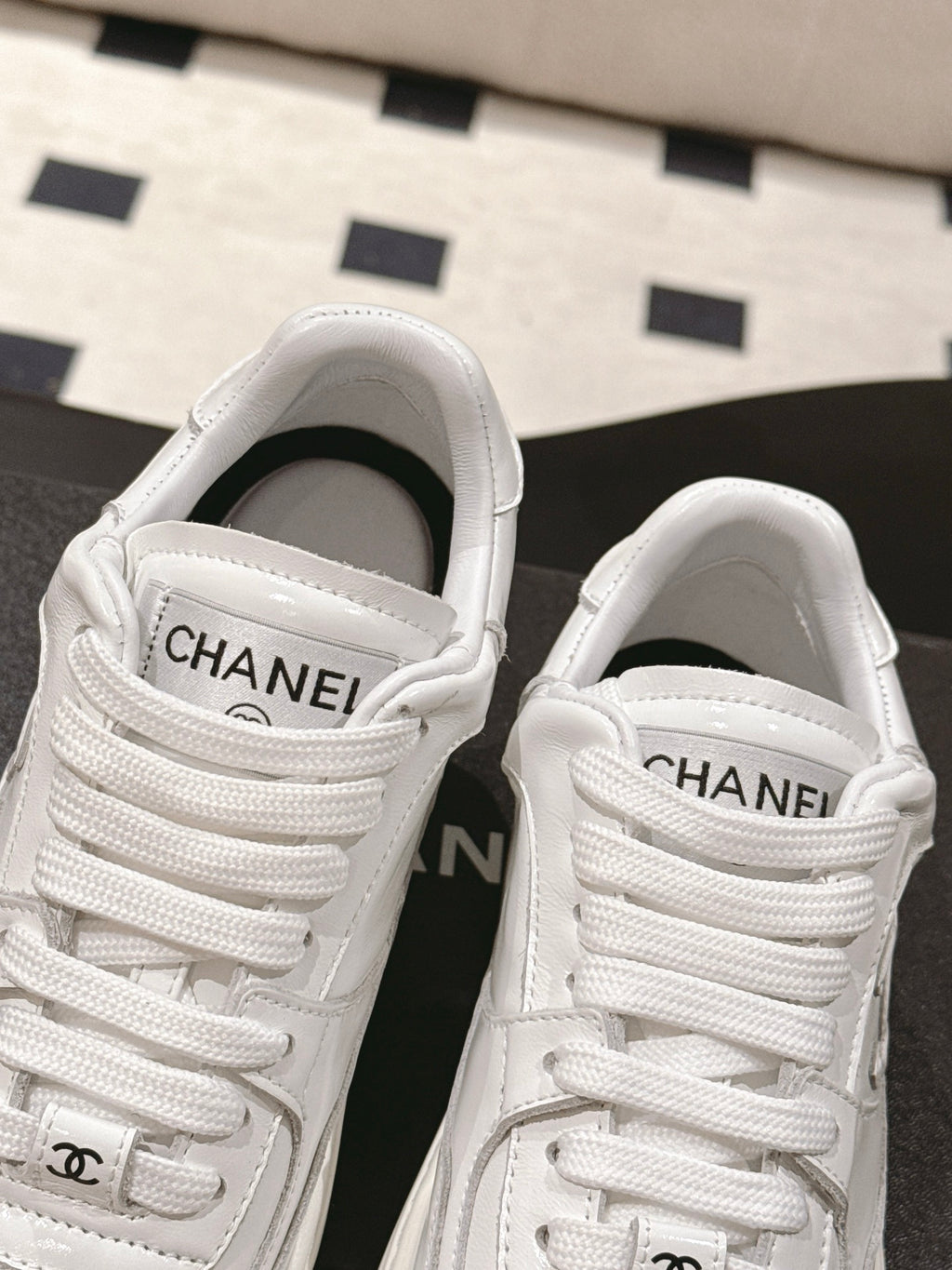 White Chanel sneakers showing padded tongue with CHANEL lettering
