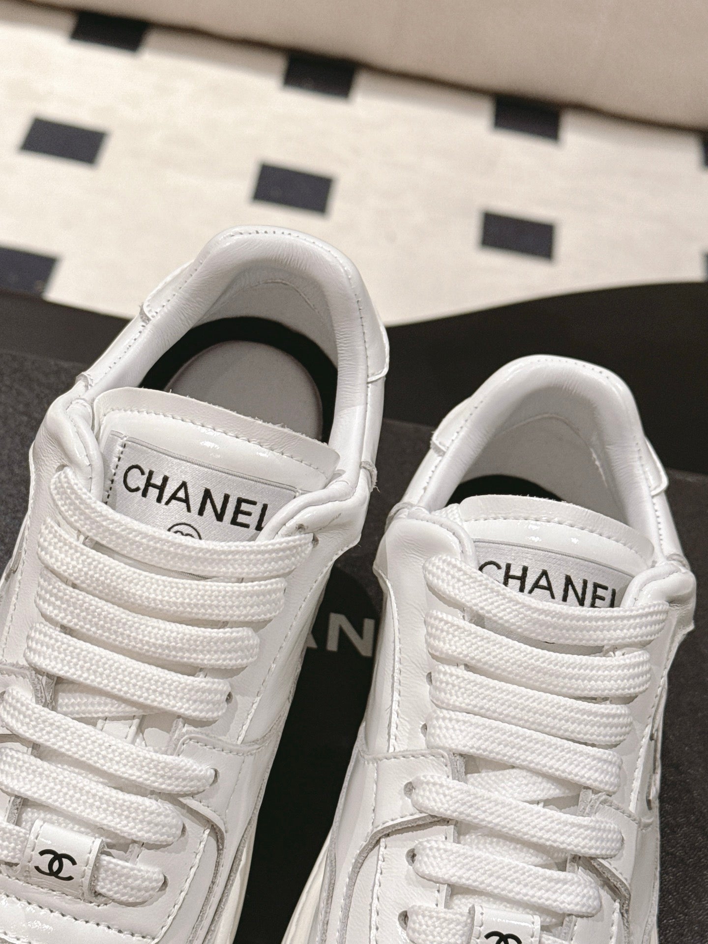 White Chanel sneakers showing padded tongue with CHANEL lettering