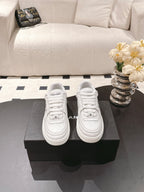 Pair of white low-top sneakers on a box, with laces and side logo panels