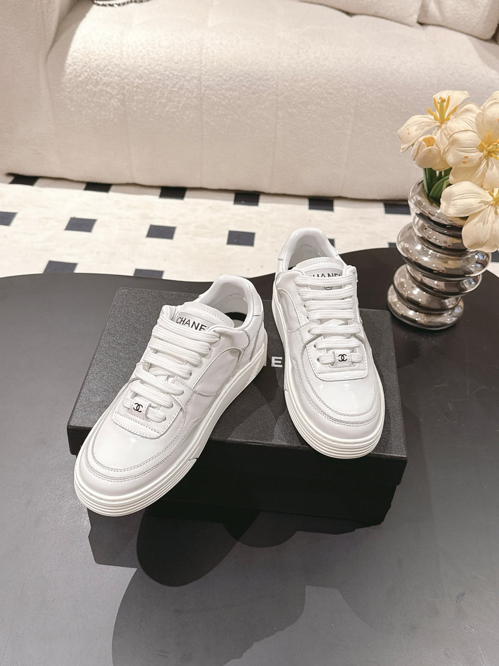 White Chanel low-top sneakers on display with side CHANEL logo