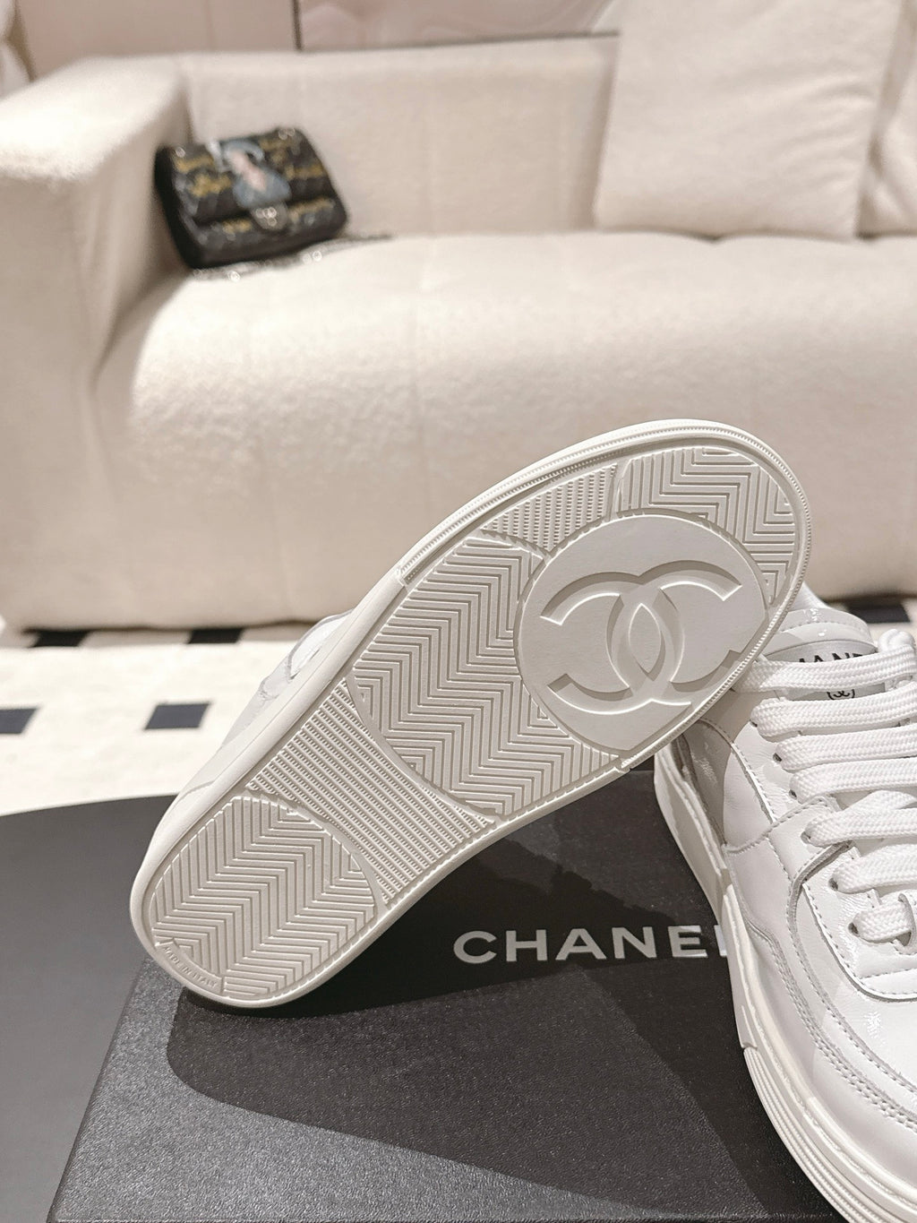 White sneaker outsole close-up with herringbone tread and circular emblem