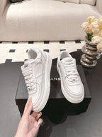 White low-top sneakers with lace-up front and side logo strap detail
