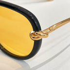 Gold metal temple detail on dark sunglasses with amber tinted lens
