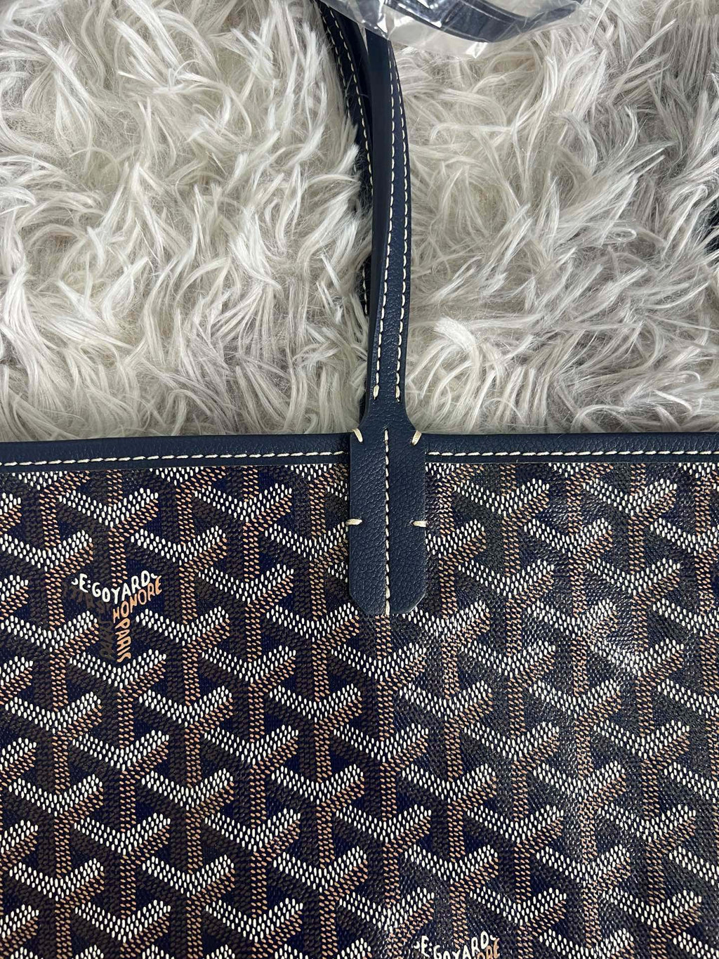 Goyard crossbody bag front, dark monogram pattern with stitched trim and logo
