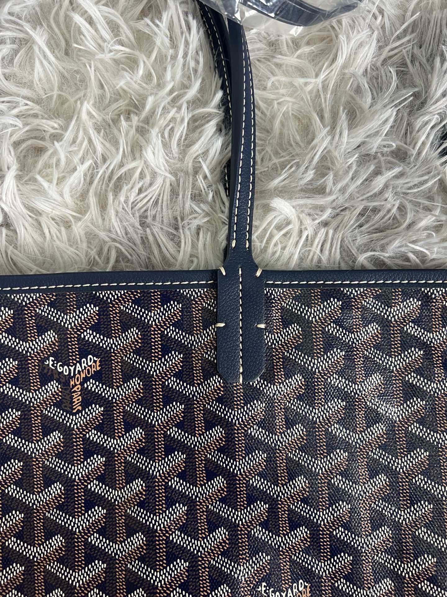 Goyard crossbody bag front, dark monogram pattern with stitched trim and logo