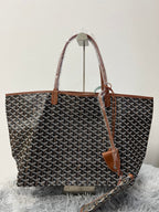 Goyard patterned tote bag side view with brown leather handles and hanging tag
