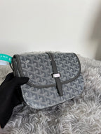 Monogram shoulder bag in dark gray/black with flap and black leather strap, held in hand