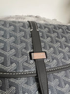 Close-up of crossbody bag flap strap and logo plaque on dark monogram canvas
