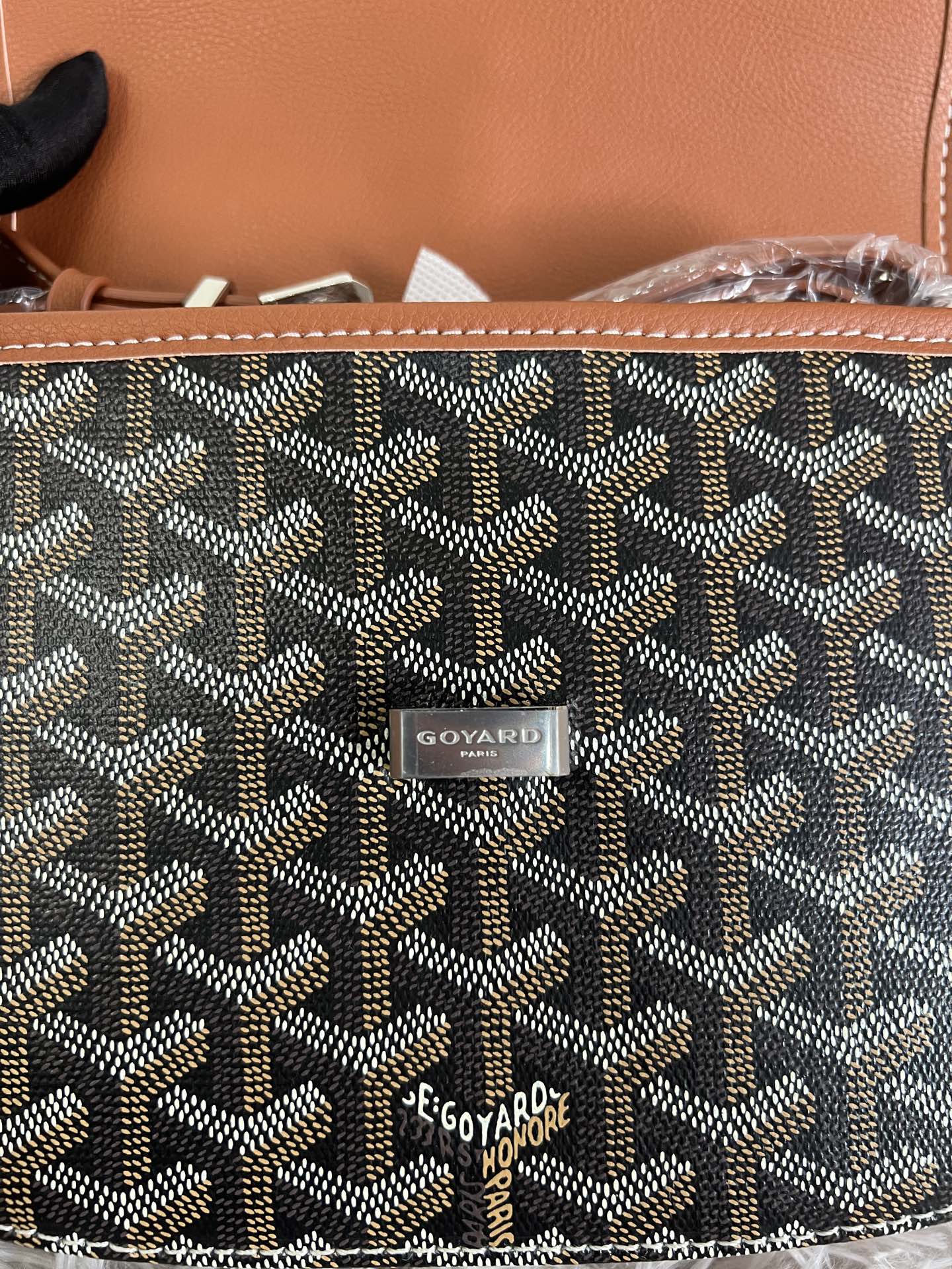 Goyard monogram bag close-up with tan leather stitching and Goyard logo patch