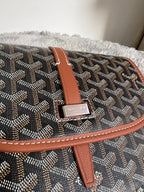Tan leather strap with metal buckle on dark monogram crossbody bag flap