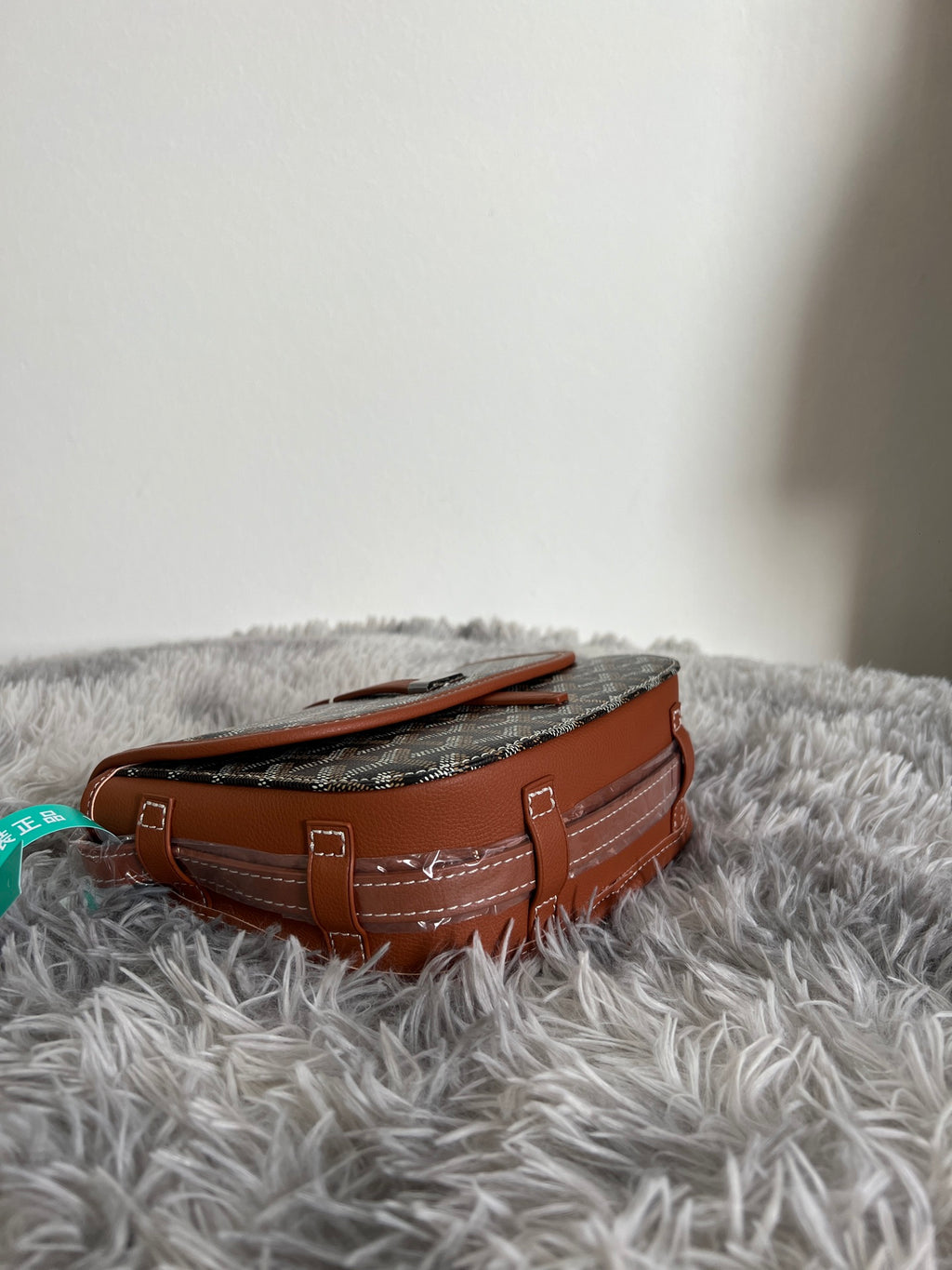 Monogram shoulder bag side view with tan leather handles and stitched seams