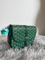 Green patterned Goyard crossbody bag with leather strap and hanging brand tag