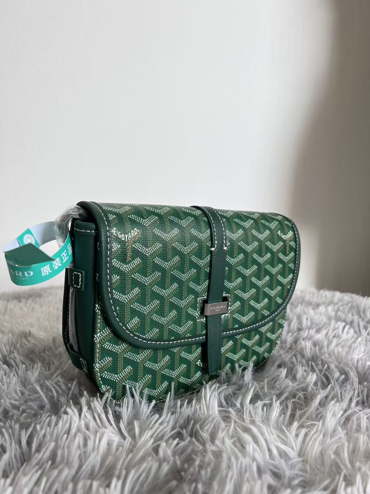 Green patterned Goyard crossbody bag with leather strap and hanging brand tag