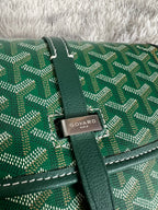 Close-up of green patterned Goyard bag with leather strap and front brand clasp