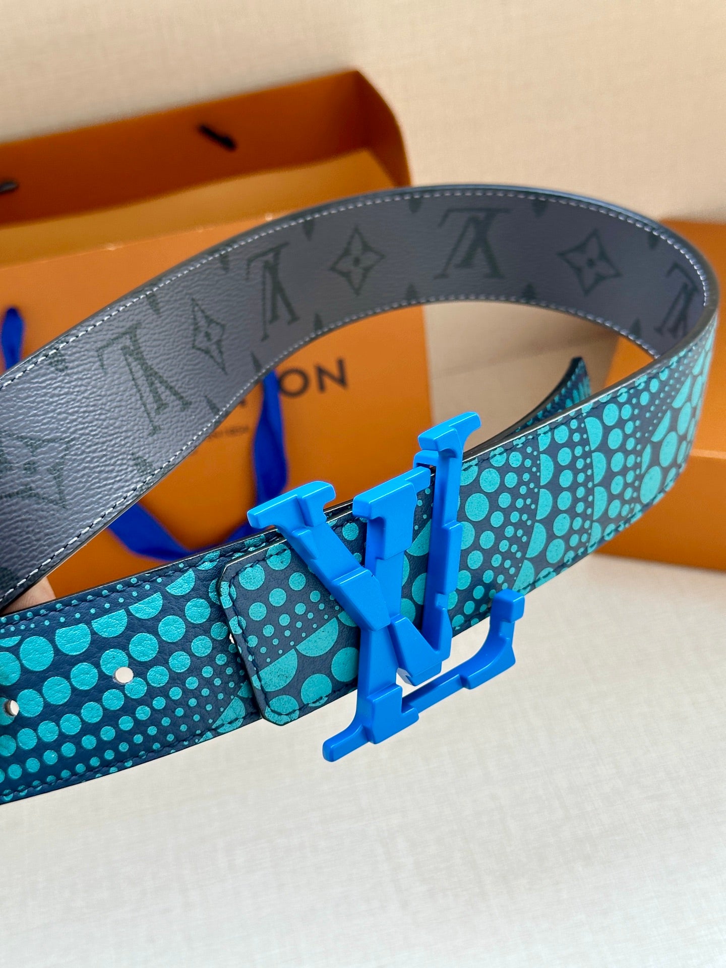Louis Vuitton belt detail showing turquoise polka-dot strap and blue metal buckle