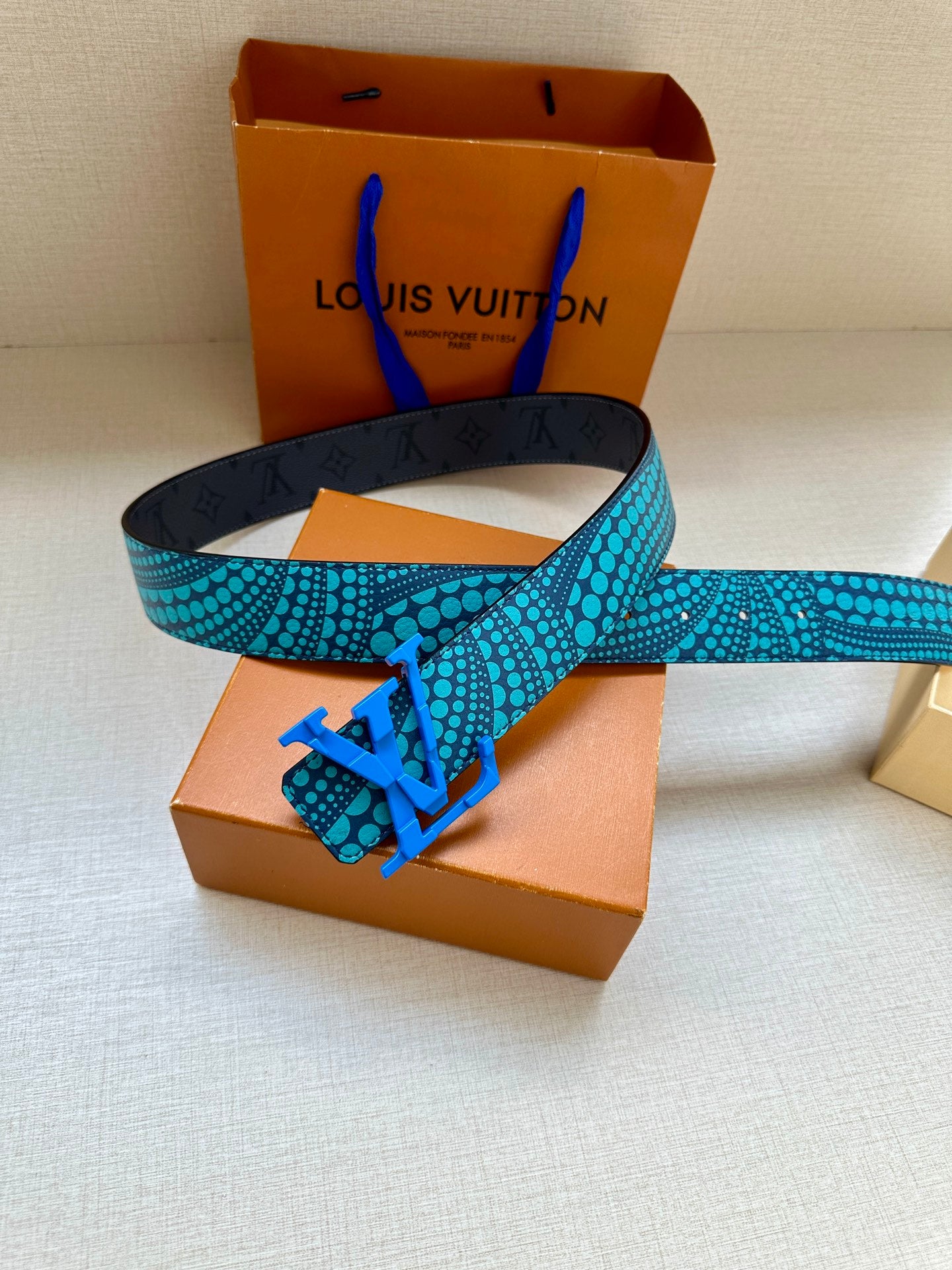 Louis Vuitton belt on box: turquoise patterned strap with blue LV buckle and dark backing