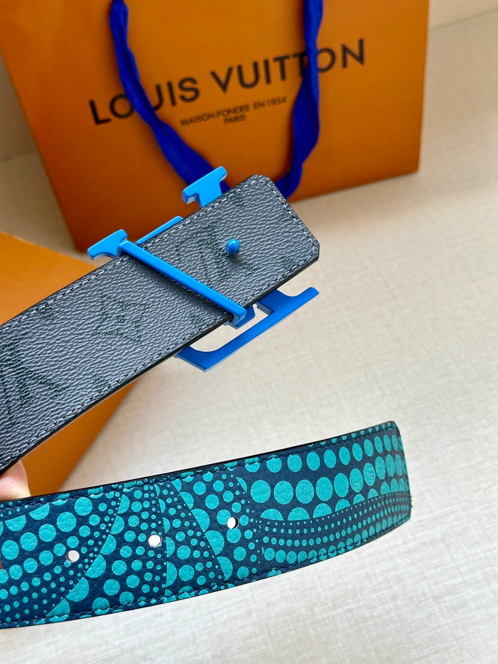 Louis Vuitton belt end with blue pin buckle and dark leather underside, turquoise strap