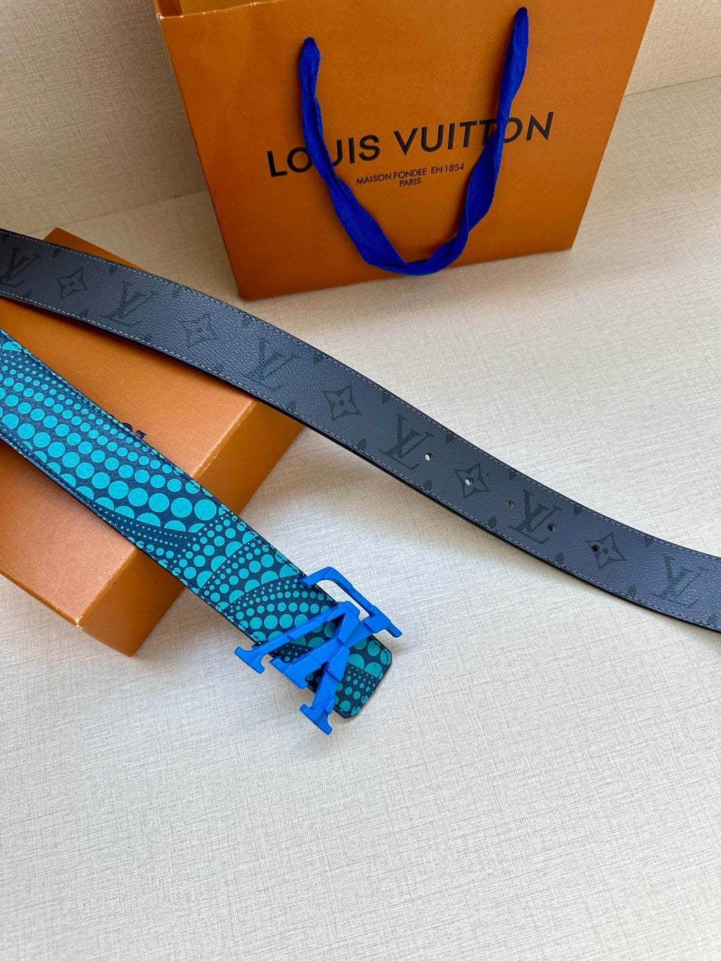 Louis Vuitton belt with turquoise patterned strap and blue pin buckle, laid flat