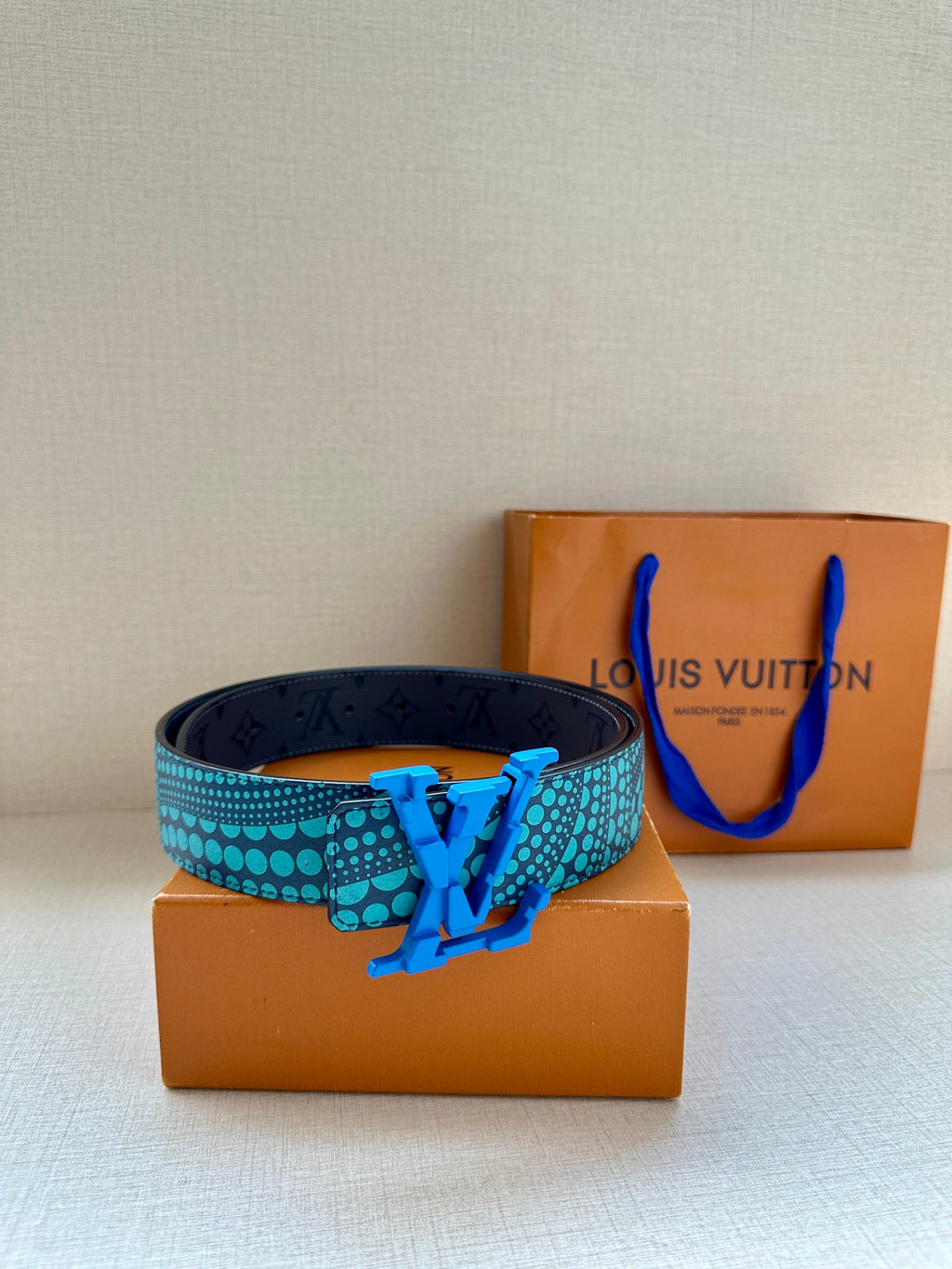 Louis Vuitton belt with turquoise dotted strap and blue buckle, coiled with box