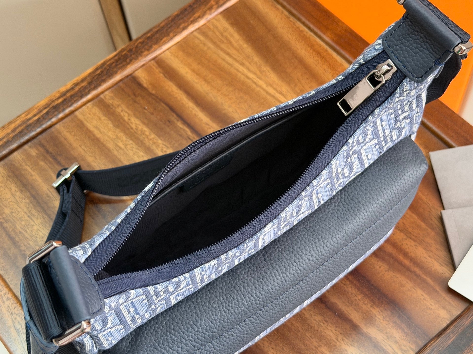 Dior bag open view with dark interior and blue monogram exterior plus zip closure