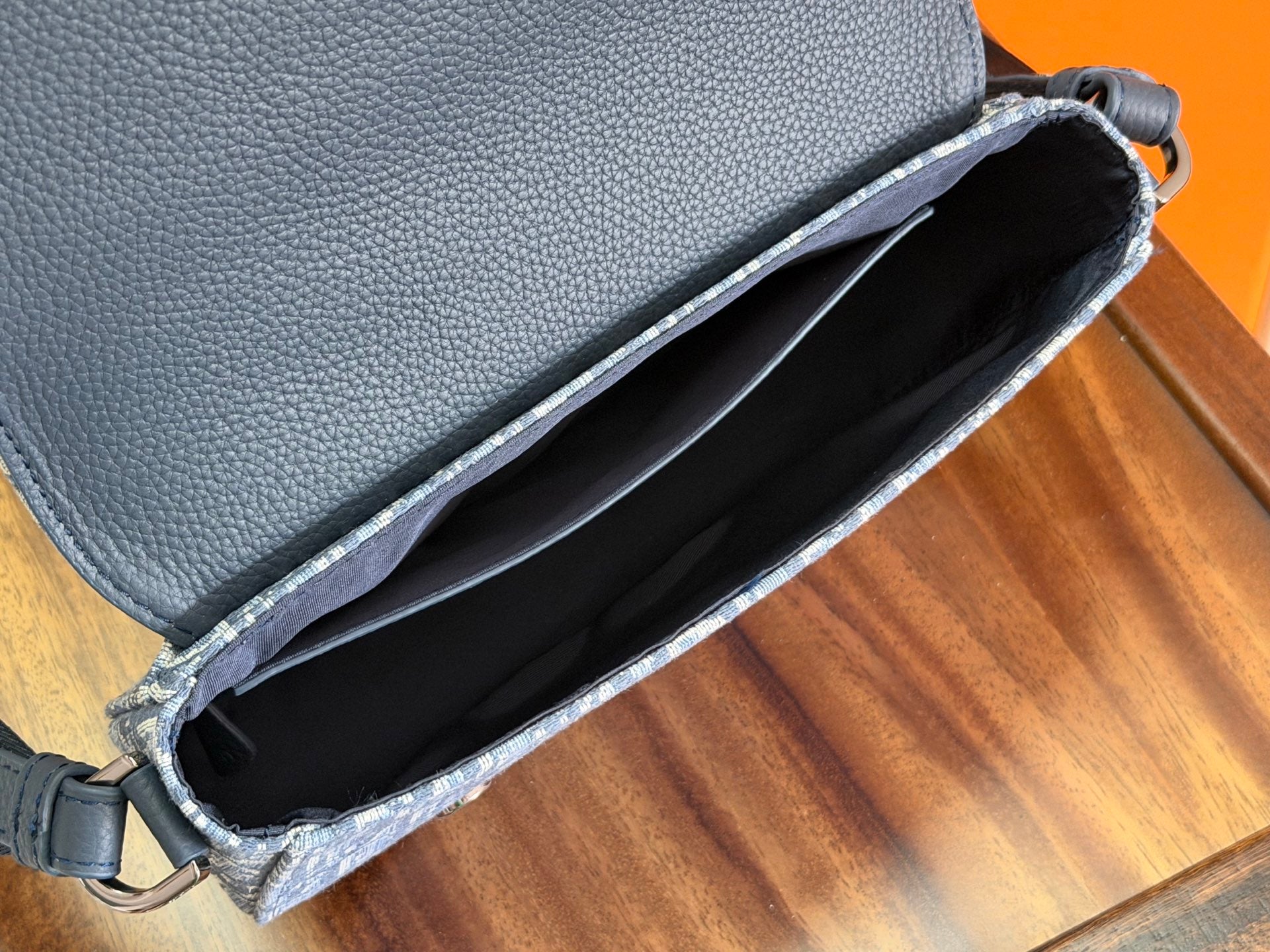 Dior men's bag interior view with black lining and open top on blue monogram canvas