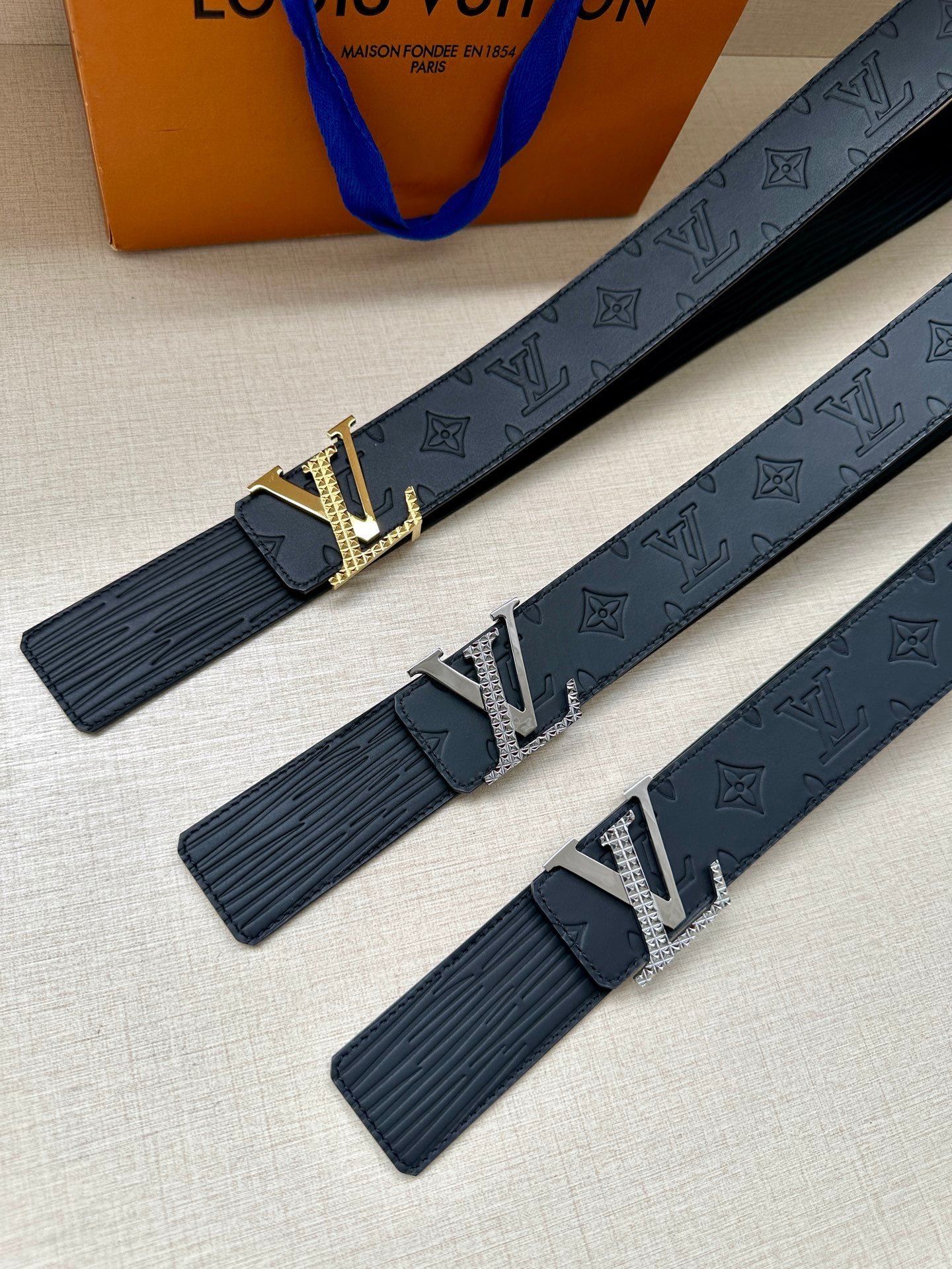 Three dark navy Louis Vuitton belts with embossed monogram and silver-tone LV buckles.