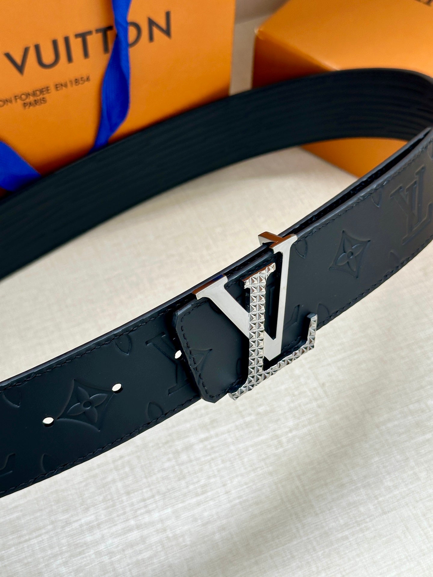Dark navy Louis Vuitton belt close-up with textured strap and silver-tone LV buckle.