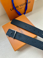 Navy Louis Vuitton belt with embossed pattern and silver-tone buckle, side view.