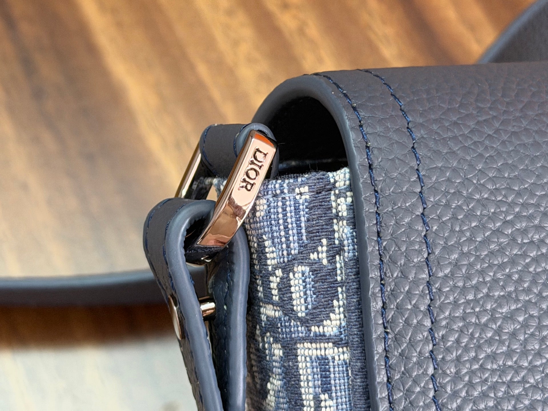 Dior crossbody bag side detail with blue leather loop and strap attachment