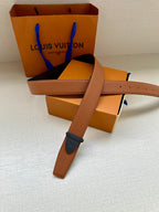 Tan leather belt with dark blue buckle, long strap tail visible