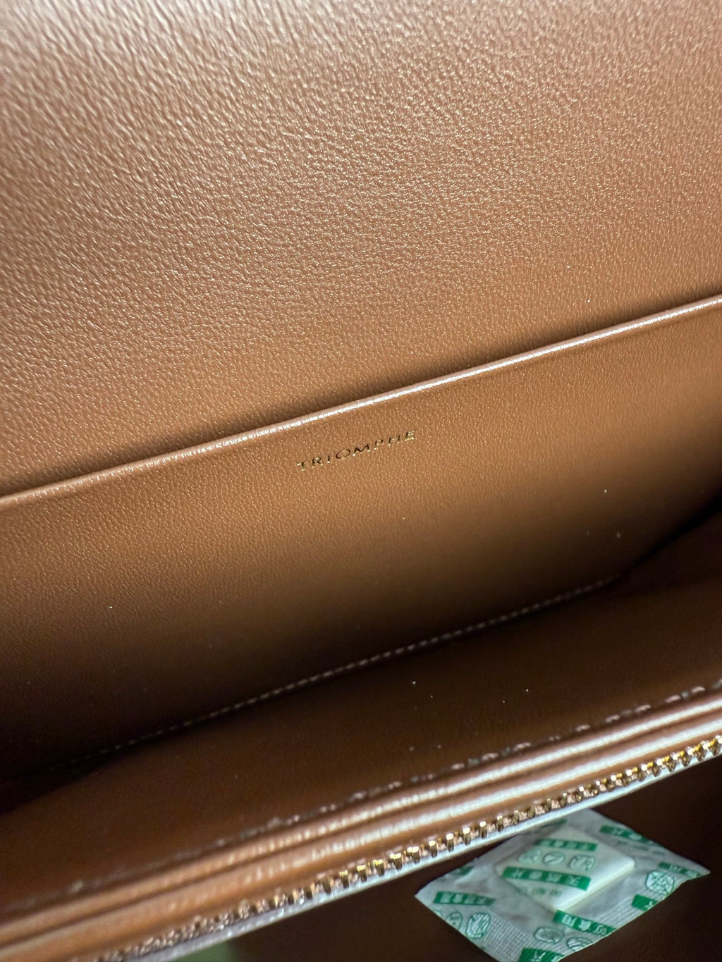Celine bag interior with paper notes and gold zipper trim in textured brown leather