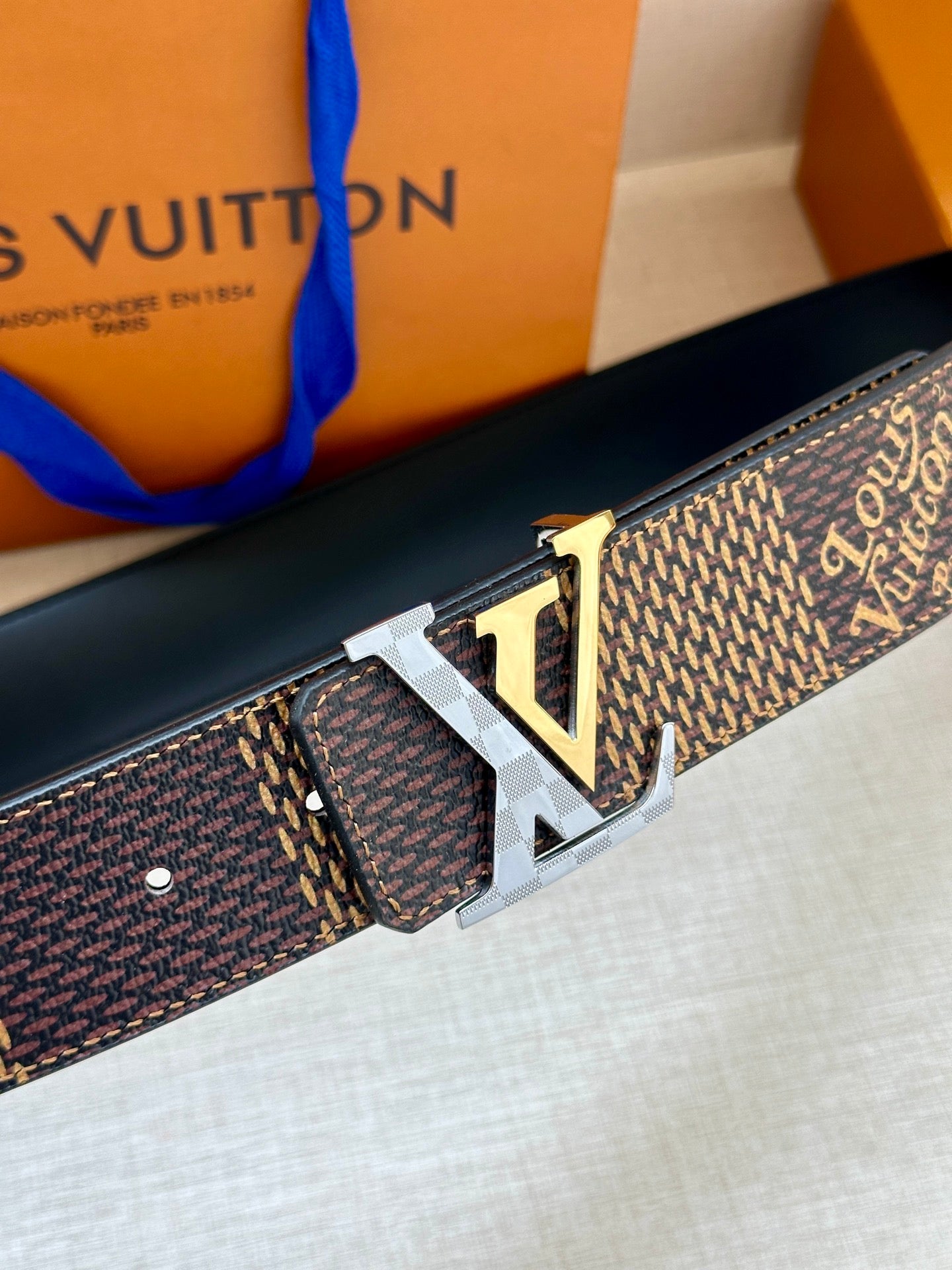 Louis Vuitton belt close-up with oversized LV gold-tone buckle and dark monogram print