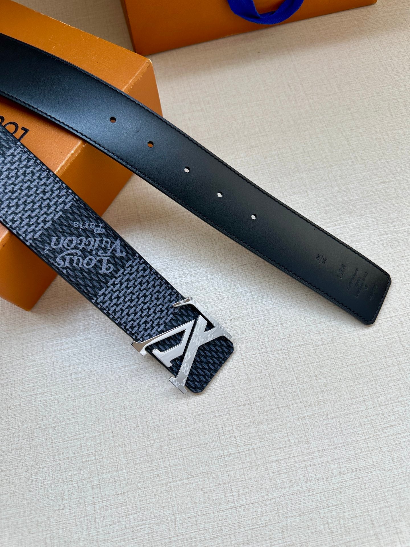 Two dark blue belt straps with silver buckle hardware and punched holes