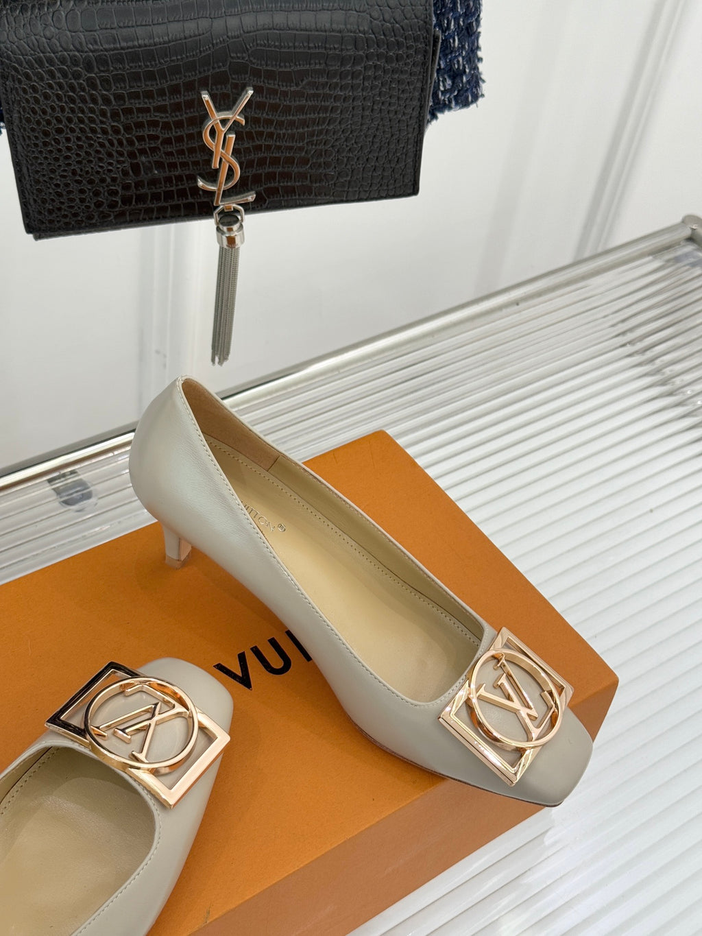 Cream Louis Vuitton pumps with gold logo buckle detail and low heel