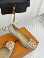 Cream Louis Vuitton pumps with gold logo buckle detail and low heel