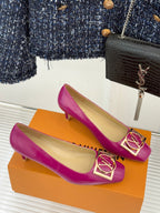 Pink Louis Vuitton heels on orange box, featuring gold LV logo buckle on toe