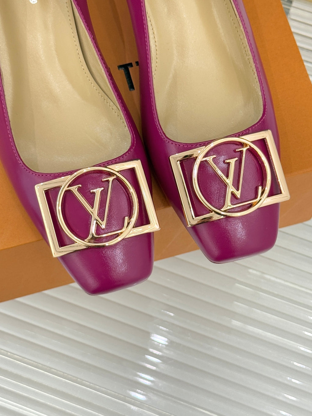 Close-up of pink Louis Vuitton heels with gold LV logo buckle trim at the toe