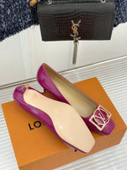 Pink Louis Vuitton heels with gold LV logo buckle detail, laid on orange box