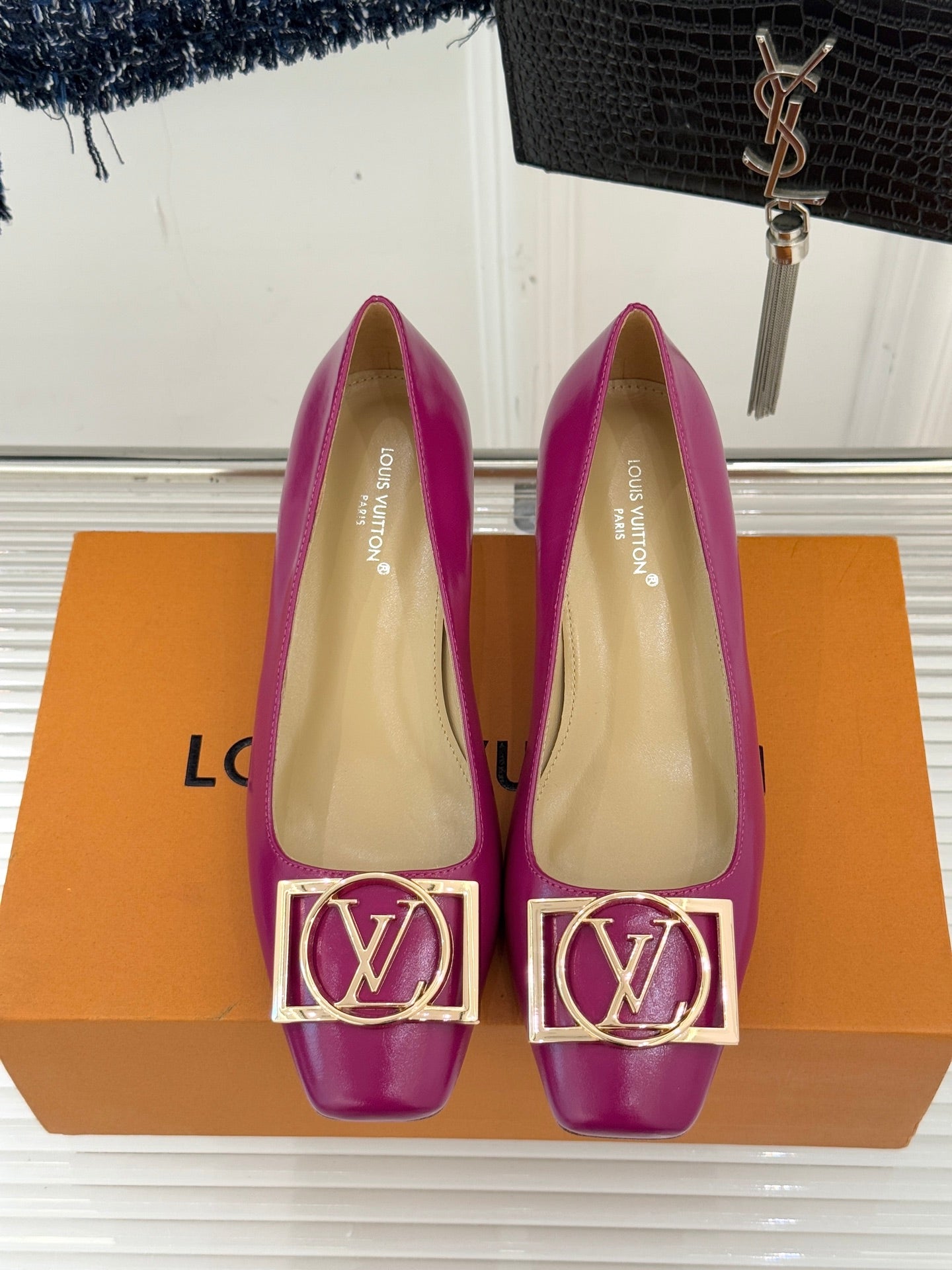 Two pink Louis Vuitton heels with gold LV logo buckle detail and pointed toe