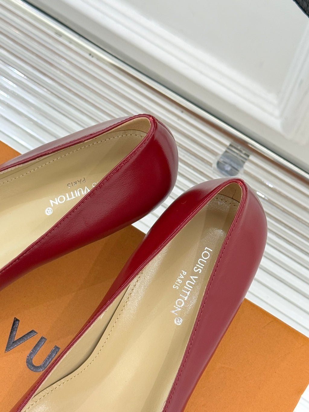 Louis Vuitton ladies red pointed-toe pumps, angled view with beige lining and logo